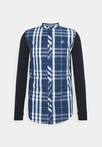 Long-sleeve shirt featuring a blue and white checkered pattern on the front and solid black sleeves. Styled with a button-up collar.