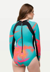 Heldräkt med lång ärm i turkos med svarta detaljer. Har ett blommönster i rosa och orange. Dragkedja bak. Slät och elastisk material.