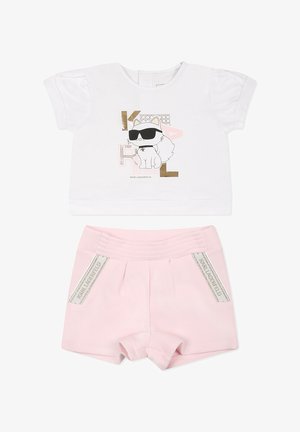 T-shirt blanc à manches courtes avec un graphisme de chat et des accents dorés, associé à un short rose texturé avec une large taille et des détails de logo.