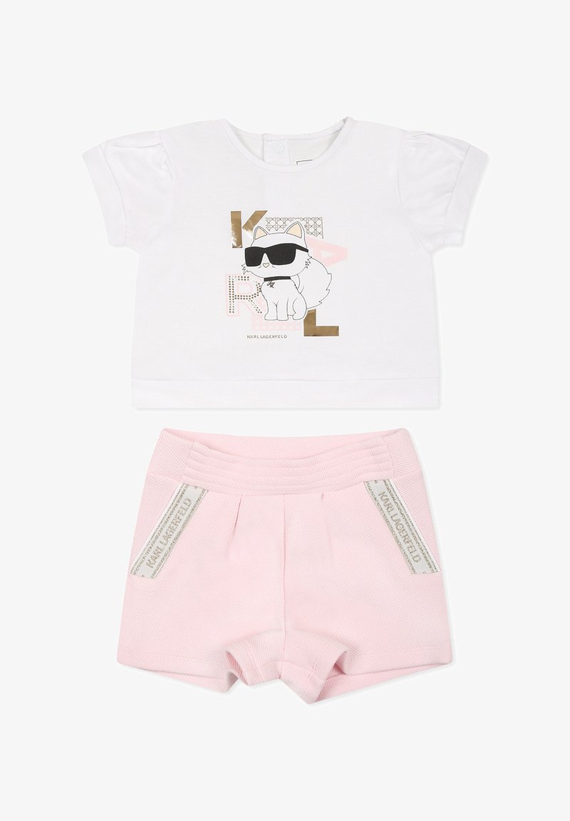 T-shirt blanc à manches courtes avec un graphisme de chat et des accents dorés, associé à un short rose texturé avec une large taille et des détails de logo.
