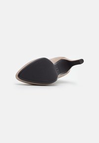 Scarpa con tacco alto, con una tomaia nuda liscia, punta affusolata e suola in gomma nera. Presenta un design elegante e accenti minimalisti.