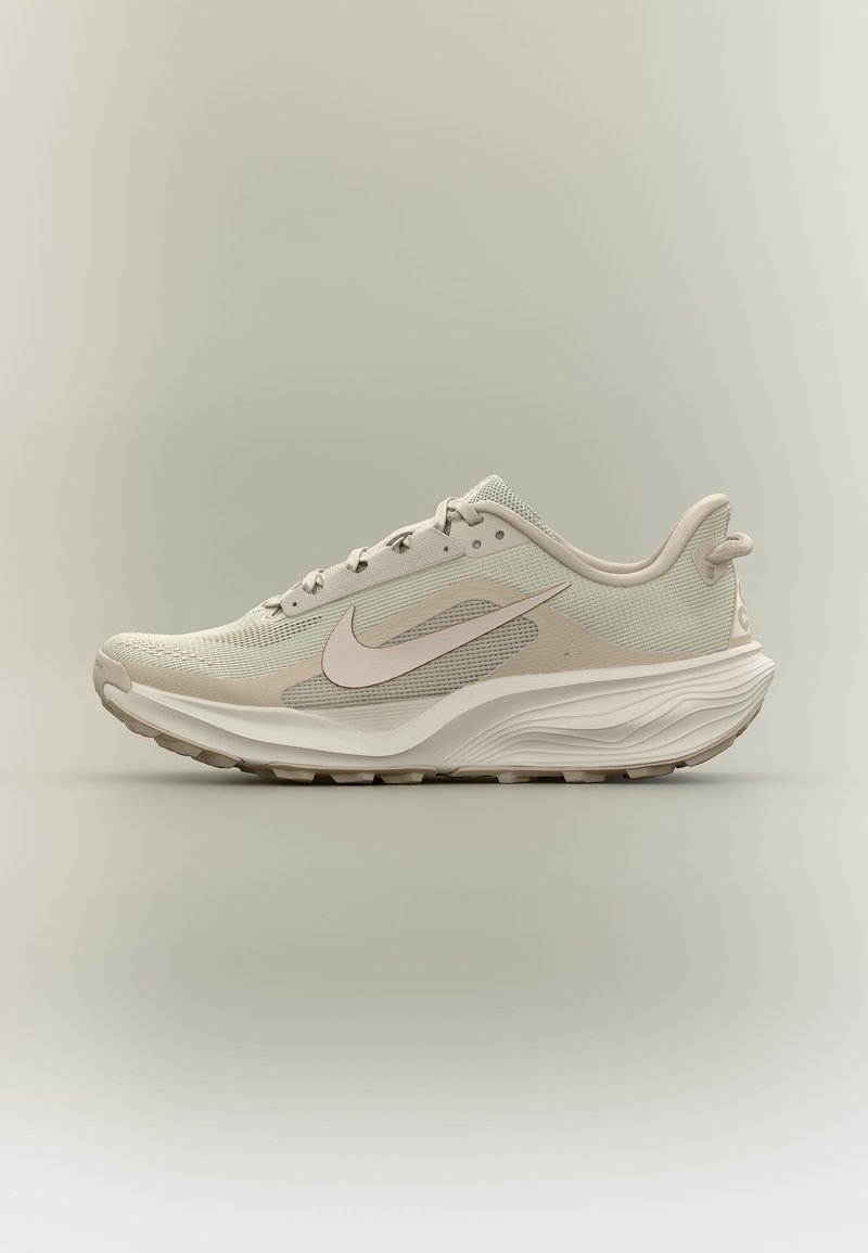 Ανοιχτό μπεζ παπούτσι τρεξίματος Nike με ανώτερο μέρος από διχτυωτό υλικό, λευκή σόλα, λογότυπο swoosh στο πλάι και επενδεδυμένο γιακά για άνεση, εμφανίζεται σε πλευρικό προφίλ.