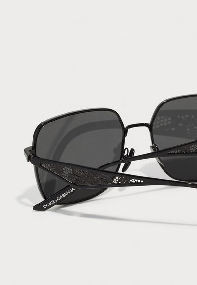 Mustad mustad raami, tumedad objektiivid ja keerukate väljakaevamistega mustadel käepidemetel, millel on "DOLCE & GABBANA" bränding.