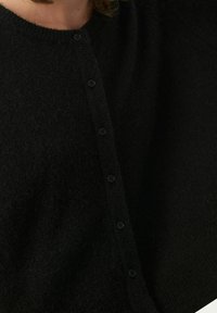 Svart ullcardigan med rund halsringning, framknäppning med sex mörka knappar och ett mjukt, strukturerat tyg.