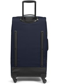 Valigia da viaggio blu navy con manico rigido, superficie liscia, base nera e quattro ruote per la mobilità. Presenta accenti protettivi in gomma.