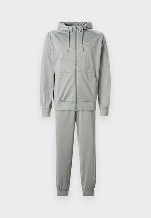 Tuta sportiva grigio chiaro composta da felpa con cappuccio con zip e coulisse regolabili e pantaloni abbinati a gamba affusolata con polsini elastici.