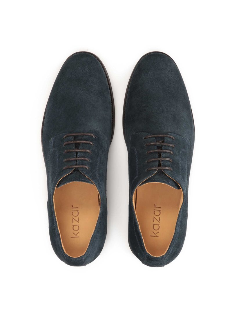 Chaussures en daim bleu foncé avec une texture lisse, un design à lacets et des lacets marron contrastants. L'intérieur présente une doublure beige.