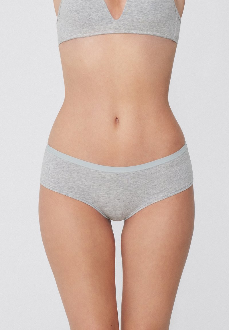 Šedá bavlněná souprava spodního prádla s měkkým pásem. Podprsenka má design s V-výstřihem, zatímco kalhotky jsou ve stylu boyshort s plochým páskem.