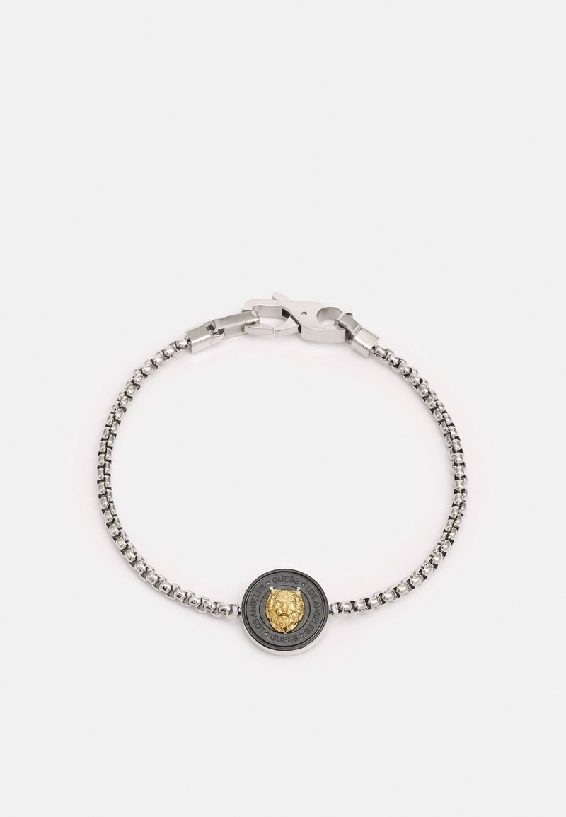 Bracelet chaîne en argent avec un emblème rond tête de lion noir et doré, sécurisé par un fermoir mousqueton argenté.