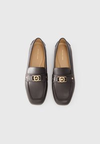 Brown leather loafers featuring a square toe, gold logo hardware, and contrasting stitching. Smooth texture with a flat sole.