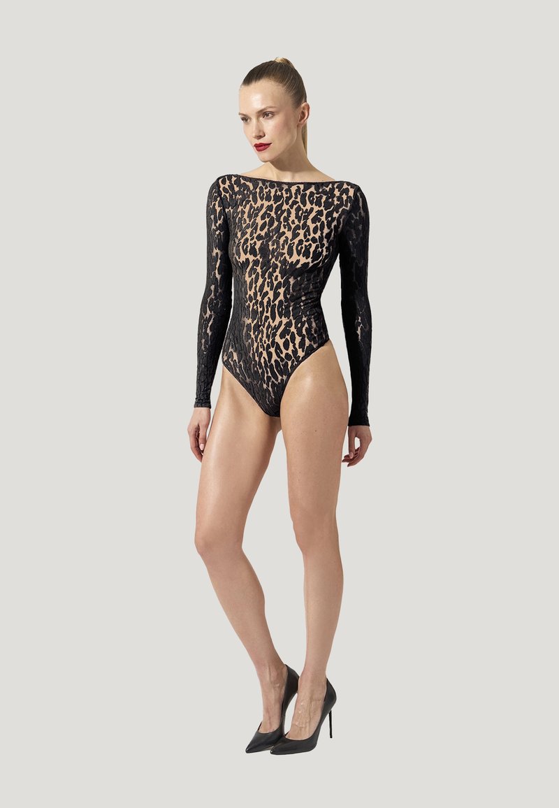 Bodysuit noir à manches longues avec un motif léopard transparent, col montant et silhouette ajustée. Porté avec des talons hauts noirs.