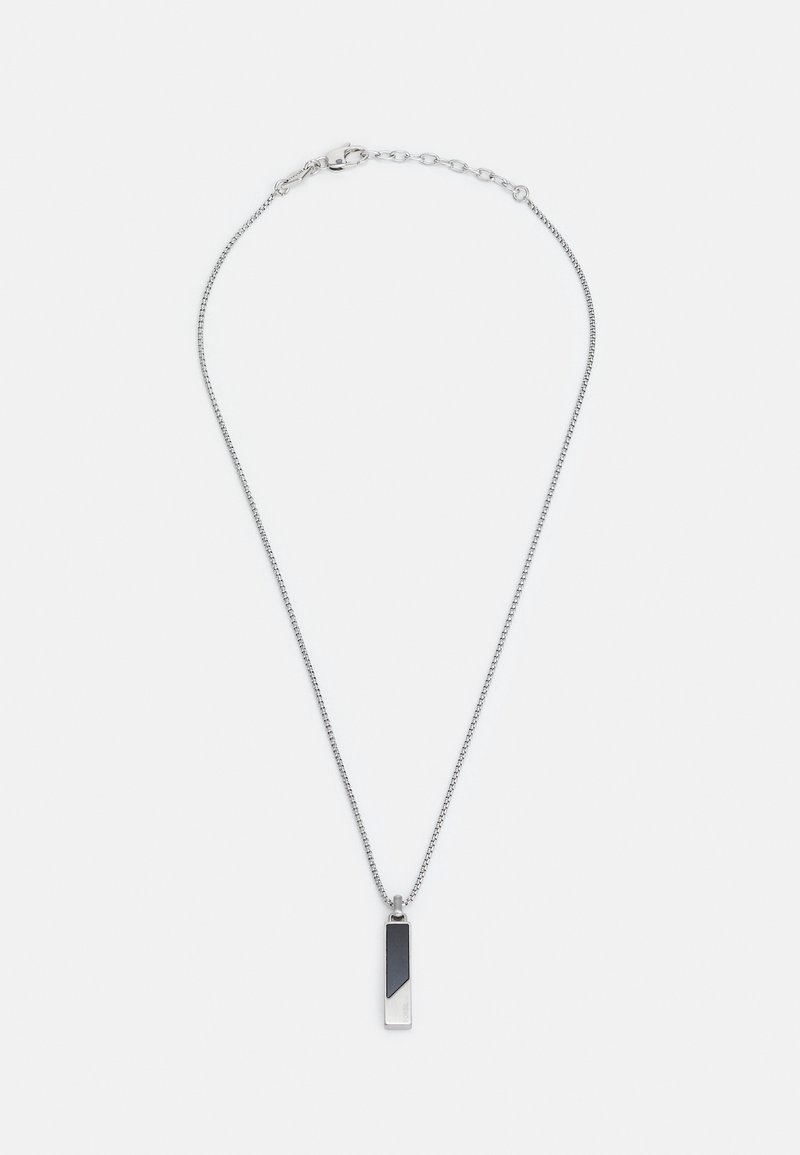 Collier chaîne en argent avec un pendentif rectangulaire noir et argent et une fermeture à mousqueton sur fond blanc.