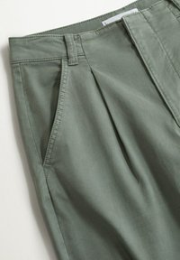 Světle zelené kalhoty vyrobené z husté tkaniny, s předními záhyby, postranními kapsami a pasem s poutky na opasek.