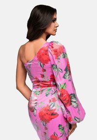Robe rose à une épaule avec un motif floral rouge audacieux, silhouette ajustée et manche bouffante. Tissu lisse avec une texture douce.