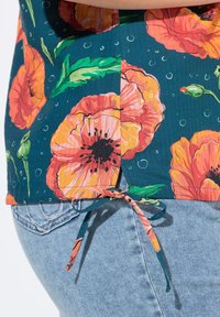 Blomstret top med en mørk teal farve dekoreret med orange og lyserøde valmuer, grønne blade og et bundet detalje på siden.