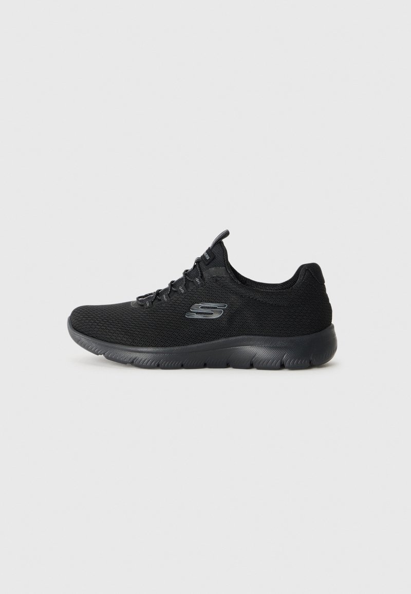 Baskets de sport noires Skechers en tissu mesh, avec lacets à l'avant et semelle épaisse et rembourrée sur un fond clair uni.