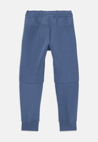 Blaue Stretchleggings mit elastischem Bund, glatter Textur und Kniepatch-Details. Enger Schnitt mit schmal zulaufenden Bündchen am Knöchel.