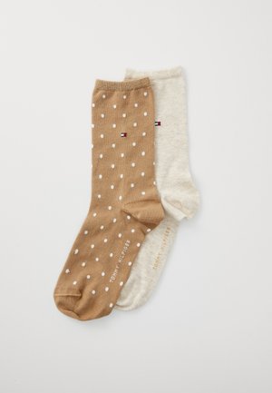 Twee paren sokken: één lichtbruin met witte stippen, de andere beige; van een katoenmix met logodetails bij de boord.