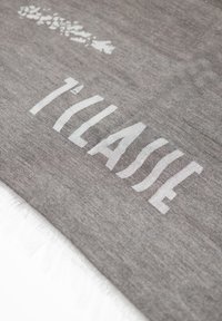 Tessuto grigio con bordi frangiati, caratterizzato da testo bianco "TILASSE" in un font audace e moderno. Texture liscia con leggere variazioni di tonalità.