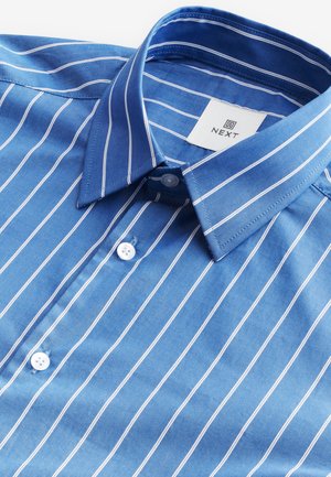 Chemise en coton bleue avec des rayures blanches, col boutonné, et une étiquette indiquant "NEXT". Comprend des boutons blancs et une texture douce.