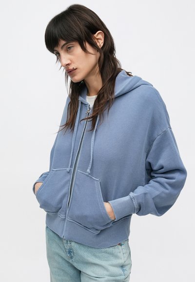 Φούτερ με φερμουάρ σε απαλό μπλε ύφασμα, διαθέτει τσέπη καγκουρό, ριμπ μανσέτες και ευρύχωρη κουκούλα. Χαλαρή εφαρμογή με μινιμαλιστικές λεπτομέρειες.