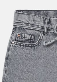 Grå denimjeans har høy midje, synlig søm, en frontlomme med kobberfarget detaljer, og en avslappet passform.