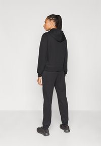 Μαύρο φούτερ με κουκούλα, μπροστινή τσέπη και ρυθμιζόμενο κορδόνι, σετ με ταιριαστά τζόγκερ, με ελαστικές μανσέτες και άνετη εφαρμογή.