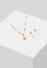 Goldkette mit einem großen weißen Perlenanhänger und passenden Perlen-Ohrsteckern, die glatte Oberflächen und ein zartes Kettendesign aufweisen.