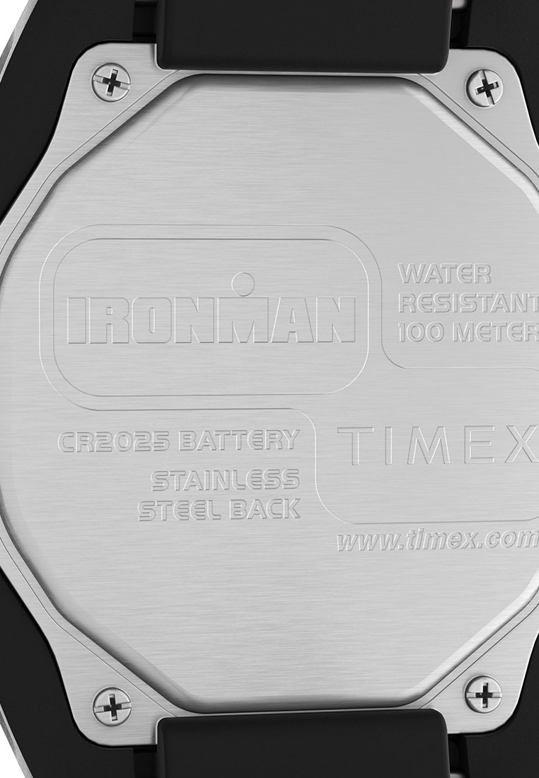 La parte trasera del reloj de acero inoxidable presenta texto grabado: "IRONMAN," "BATERÍA CR2025," "RESISTENTE AL AGUA HASTA 100 METROS," y "TIMEX," con acentos de plástico negro.