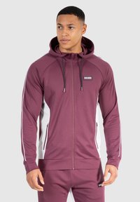 Bordeaux zip-up hoodie med hvide sidepaneler, snøre i hætten og logo patch. Glat stof med lange ærmer og frontlommer.