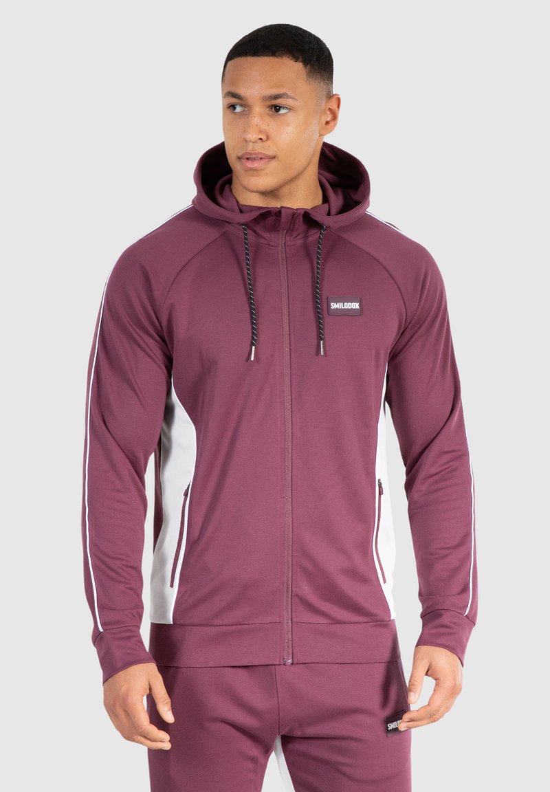 Bordeaux zip-up hoodie med hvide sidepaneler, snøre i hætten og logo patch. Glat stof med lange ærmer og frontlommer.