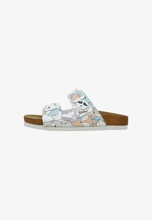 White slide sandal featuring a playful animal print design. Doubled adjustable straps and a cork-like sole provide comfort and support.