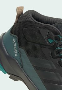 Schwarzer Mesh-Wanderschuh mit türkisfarbenen Akzenten, Gummisohle und verstärktem Absatz; mit Logo an der Seite und einem Zugtab an der Rückseite.