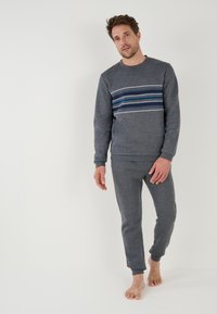 Sudadera gris y joggers a juego hechos de una tela suave. La sudadera presenta un diseño de rayas horizontales en azul y verde.