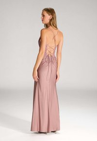 Robe de soirée rose avec un corsage ajusté et une jupe fluide. Présente un détail de dos lacé, des fines bretelles et un tissu lisse et texturé.