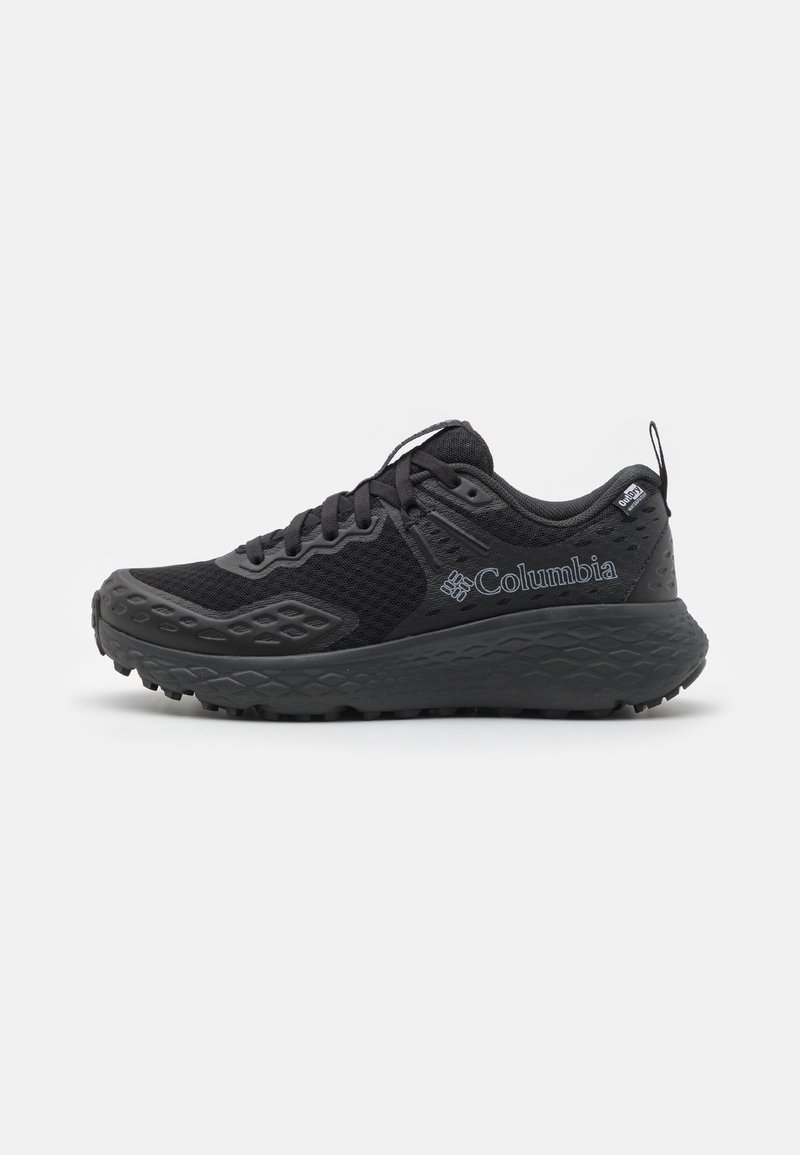 Chaussure de trail running Columbia noire avec semelle texturée, tige en mesh, lacets et étiquette imperméable "OutDry" sur le col du talon.