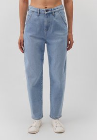 Jeans de mezclilla azul claro con cintura alta, corte recto, cinco bolsillos y costuras en contraste. Combinados con zapatillas blancas.