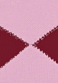 Tkanina dzianinowa z dużymi diamentowymi kształtami w głębokiej czerwieni i jasnym różu. Tekstura jest gładka z widocznymi oczkami dzianiny i lekko luźnym splotem.