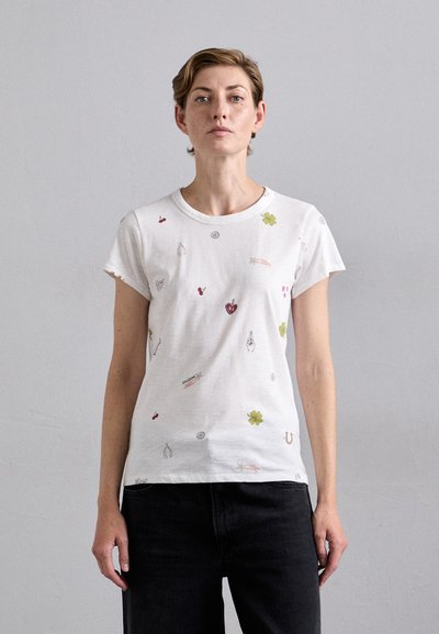 T-shirt en coton blanc à manches courtes, présentant des motifs brodés colorés incluant des fruits, des fleurs et des symboles sur l'ensemble du tissu.