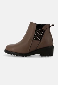 Stivaletti alla caviglia in pelle marrone con pannello laterale testurizzato decorato con borchie metalliche, suola in gomma nera e tacco basso. Design senza lacci con linguetta posteriore per facilitare la calzata.