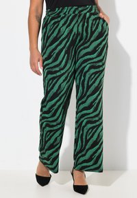 Gröna och svarta tigerstrimmiga vida byxor med elastisk midja och sidofickor, tillverkade av ett mjukt, texturerat tyg.