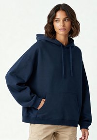 Felpa oversized blu navy realizzata in morbido tessuto, con tasca frontale, polsini a coste e coulisse regolabile sul cappuccio.