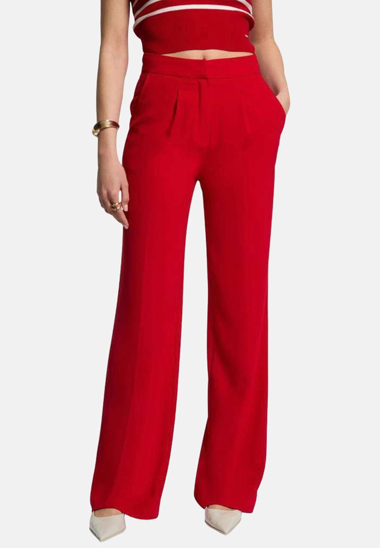 Pantalones anchos rojos de tela suave y ligera, con pliegues en el frente y bolsillos laterales, combinados con un top corto a rayas rojas y blancas.