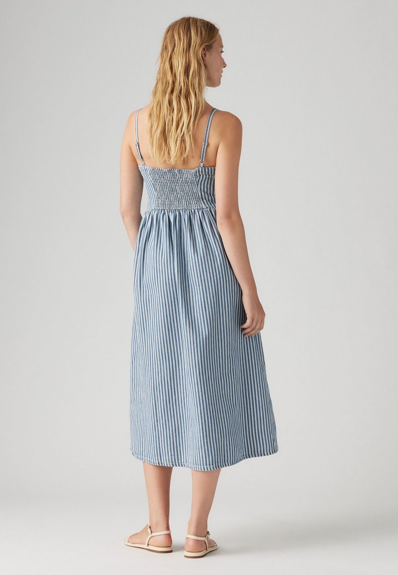 Robe midi rayée bleue et blanche avec bretelles spaghetti, corsage smocké et jupe fluide. Un tissu léger avec une coupe décontractée.