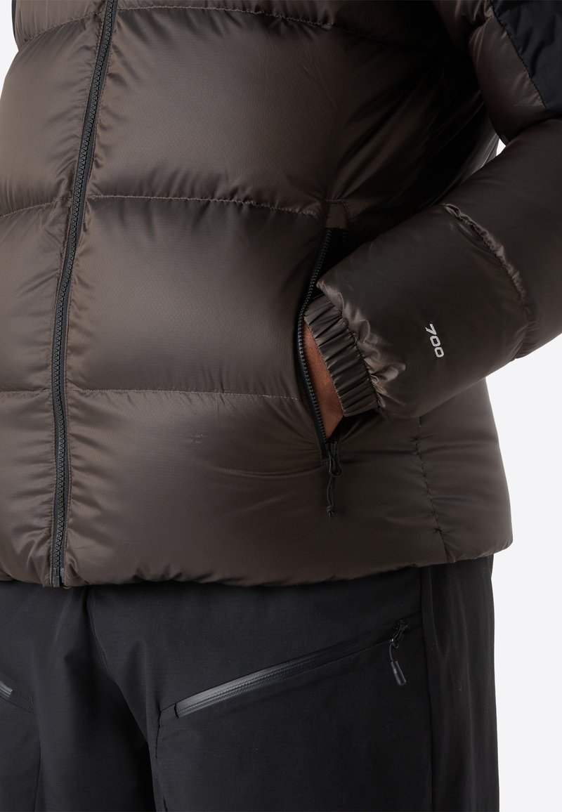 Bronze Puffershirt mit einem Reißverschlussfach, ausgestattet mit einer Füllkraft von 700. Weicher, gesteppter Stoff und elastische Bündchen für Wärme.