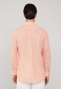 Camisa de manga larga con finas rayas verticales naranjas y blancas, cuello de botón, pliegue en la espalda y puños con un botón.