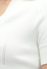 Camisola branca de malha com textura canelada, mangas curtas e decote em V. Apresenta linhas verticais subtis e detalhes delicados de costura.