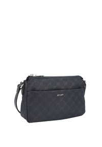 Svart tygväska med texturerat mönster, dragkedjestängning och justerbar axelrem. Har logotyp på framsidan och ytterficka.