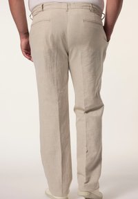 Beige Leinenhosen mit lockerer Passform, ausgestattet mit zwei Gesäßtaschen und einer glatten Textur. Das Design hat einen einfachen, klaren Look.