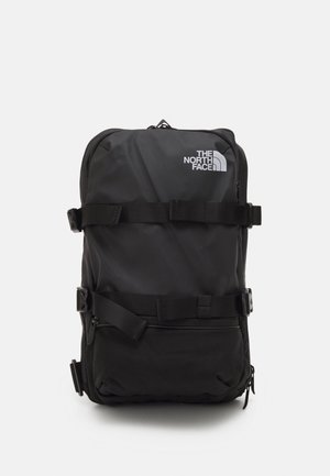 Mochila rectangular negra con correas frontales y el logo de The North Face en la esquina superior derecha, mostrada sobre un fondo blanco.